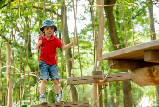 Cute child, boy, climbing in a rope playground structure, springtime